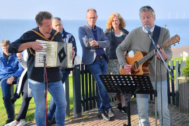 Twee mannen op accordeon en gitaar spelen een lied tijdens de opening van de wandelroute Rondje Eiland Urk
