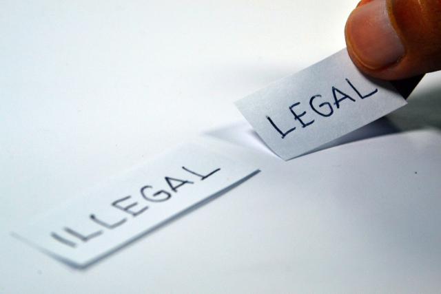 Twee strookjes papier met de tekst illegal en legal
